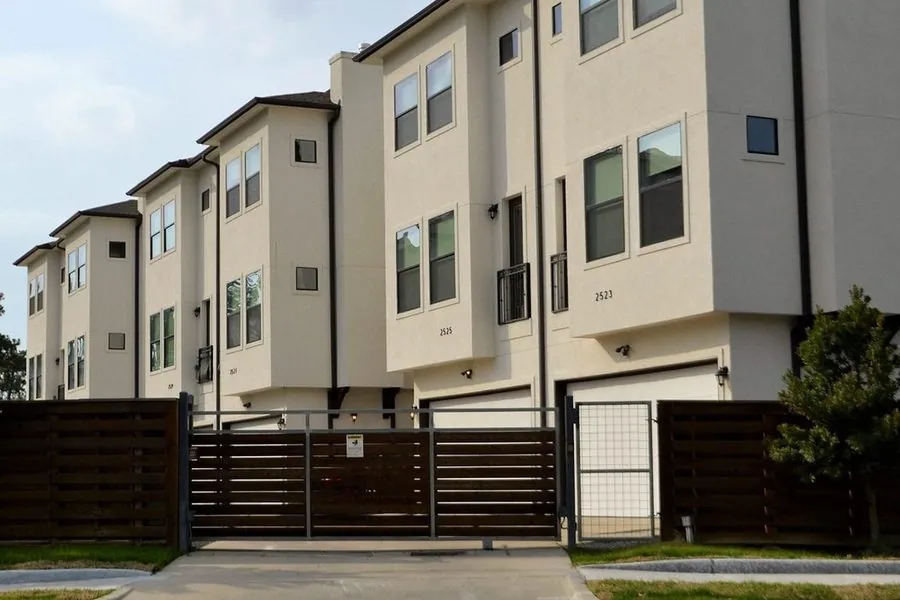 Portão de correr escuro na frente de um conjunto de casas geminadas